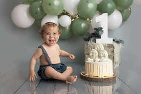 Enfant de 1 an avec cadeau d'anniversaire et arche de ballons lumineuse.