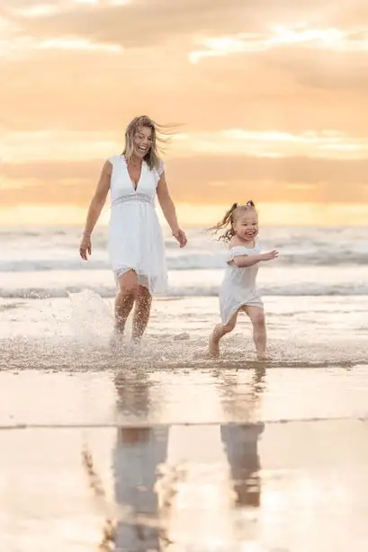 Un maman et sa petite fille qui s'amusent sur une plage.