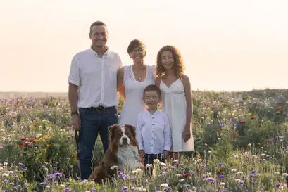 Un couple avec leurs deux enfants et leurs chien dans un champ.