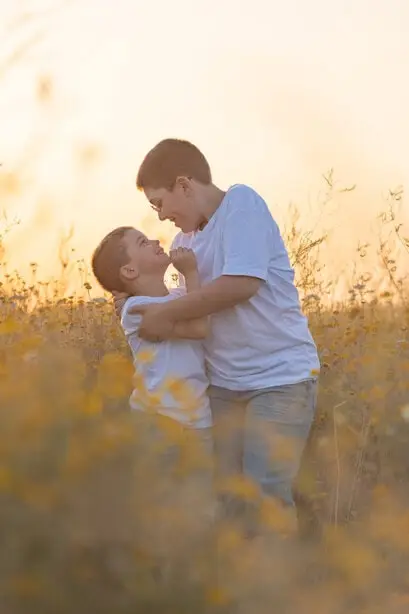 Une maman et son fils qui se regardent tendrement dans un champ.