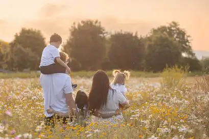 Un couple avec leurs trois enfants de dos dans un champ.