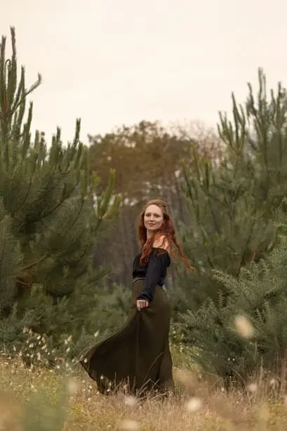 Femme en jupe verte et haut noir dans une forêt. Les tons sont verts.