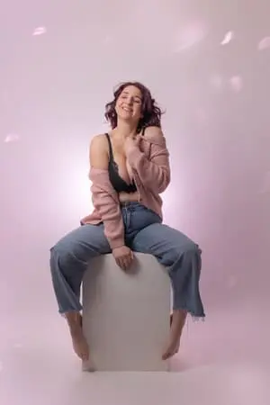 Femme en jean et soutien-gorge sur un fond rose.