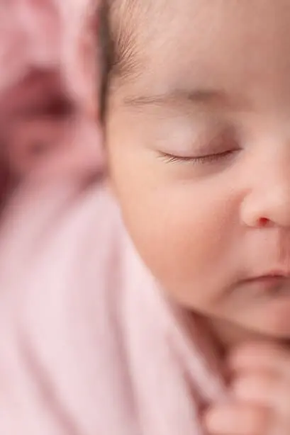Photo rapprochée du visage d’un bébé dans des tons roses.