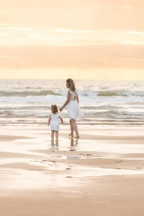 Une maman et sa petite fille sur une plage au coucher du soleil.