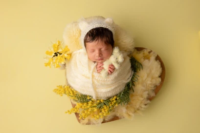 Bébé avec bonnet emmailloté avec en fond un cœur dans les tons jaunes