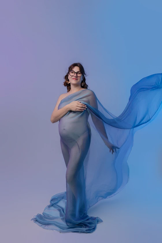 Femme enceinte en portrait dans les tons bleus lors d’une séance photo grossesse au studio.